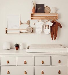 a baby's room with white dressers and toys on the shelves above them