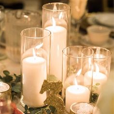 candles are lit on a table with greenery