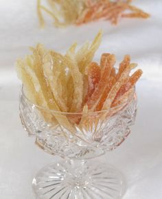 two small glass bowls filled with food on top of a white cloth covered tablecloth