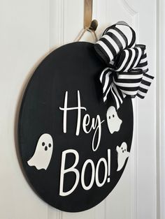 a black and white door hanger that says hey boo on it with ghost decorations