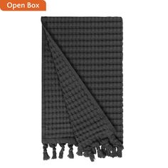 an open box towel with tassels on the bottom and one side in black