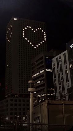 the city skyline is lit up at night with an illuminated smiley face in the sky