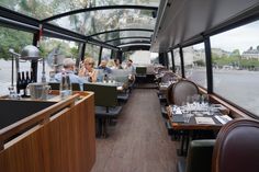 people are sitting at tables in the back of a bus with lots of windows on it