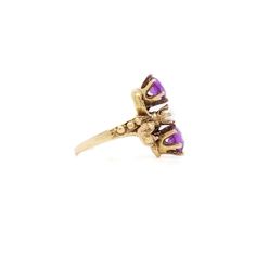 A fine toi et moi gold, amethyst, and pearl cocktail ring.  Size 2.  In 14 karat yellow gold.  The gold setting with a flower to either side of the stones and with decorative rivets/beading.  Set two round cut amethysts with a pearl in the center of the trio of stones. The amethysts have inclusions.  Simply a wonderful ring!  Date: 20th Century  Overall Condition: It is in overall good, as-pictured, used estate condition with some fine & light surface scratches and other signs of expected light wear consistent with age.  Fineness: Marked 14k for gold fineness.   Marks: Marked 14k to the shank.   Ring Size: ca. 2  Gemstone Measurements: 2 Amethyst: ca. 5.5mm diameter x 3.25mm height 1 Pearl: ca. 4mm diameter  Measurements: Height: ca. 17mm Width: ca. 18mm Depth: ca. 21mm  Weight: ca 3.3 g Vintage 14k Gold Multi-stone Amethyst Ring, Vintage Multi-stone Amethyst Ring In 14k Gold, Purple 14k Gold Ring With Rose Cut Diamonds, Purple Amethyst Ring With Rose Cut Diamonds, Purple Rose Cut Diamond Rings In 14k Gold, Purple 14k Gold Rings With Rose Cut Diamonds, Heirloom Multi-stone Purple Amethyst Ring, Anniversary Yellow Gold Three-stone Amethyst Ring, 14k Gold Multi-stone Purple Amethyst Ring