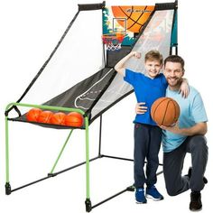 a father and son posing with basketballs in front of an arcade game machine for kids