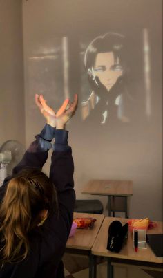 a person standing in front of a projector screen holding their hands up to the ceiling