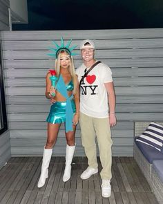 a man and woman dressed up as the statue of liberty pose for a photo in front of a wall