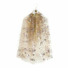 a white and gold dress hanging on a wall with sequins around it's neck