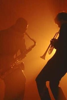 two men are playing instruments in the dark