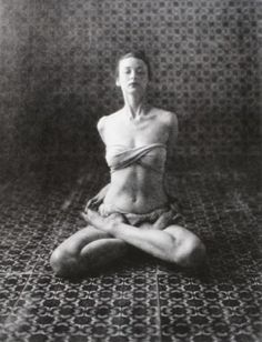 a black and white photo of a woman sitting in the middle of a yoga pose