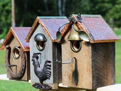 three wooden bird houses with bells on them and a rooster figurine in the middle