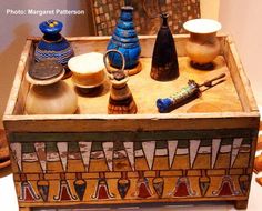 an old wooden box filled with pottery and knick knacks on top of a table