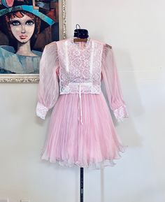 "Darling 60s sheer chiffon baby pink mini dress. It has a high ruffled lace neckline, the sleeves are sheer and puffed with accordion pleats with a tapered lace cuff, the skirt has accordion pleats, it zips up the back with a metal zipper, and the lining is silky pink nylon. It's in very good condition.  Materials: Chiffon, lace, satin Color/print: sheer Pink Maker: missing tag but doesn't appear to be handmade Era: 60's  Size: girls 8-10 Approximate Measurements Arms- 19\" Bust-  28\" Waist- 25\"-26\" Hips- 52\" fully extended Length- 29\" Condition: very good, pre-owned, the ribbon is short on one side Bust-taken from under the arm to under arm laying flat and doubled Sleeves-taken from under the arm to sleeve end Waist-taken from side to side laying flat and doubled  Length-taken from s Vintage Lace Mini Dress With Ruffles, Vintage Fitted Mini Dress With Lace Patchwork, Fitted Vintage Mini Dress With Lace Patchwork, Vintage Summer Dresses With Sheer Sleeves, Summer Vintage Dresses With Sheer Sleeves, Vintage Dresses With Sheer Sleeves For Spring, Spring Vintage Mini Dress With Lace Trim, Pink Mini Dress With Sheer Sleeves For Spring, Spring Party Vintage Pleated Dress