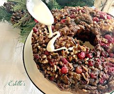 a cake with nuts and cranberries is being drizzled with icing