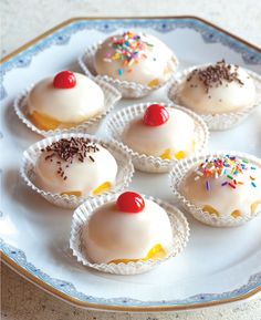 small cupcakes with white frosting and sprinkles on a plate