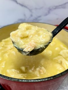 a spoon full of macaroni and cheese being held up by a ladle