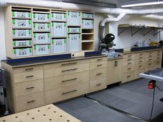 a room filled with lots of wooden cabinets and drawers next to a large machine in the background