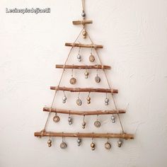 a christmas tree made out of wood sticks and balls hanging from the side of a wall