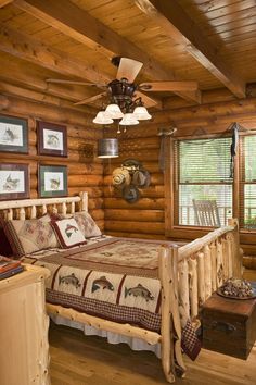 a log cabin bedroom with a bed, dresser and window in the corner that has pictures on the wall