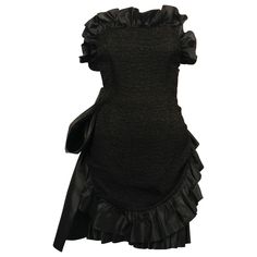 Dramatic, jet-black textured dress with satin ruffled trim and large bow designed by Yves Saint Laurent dating to the 1980's. Fully internal corset with boning at bodice. Labeled a French size 38. Approximate measurements: bust 32", waist (inner waistband) 25.5" , hips 33" (give up to 36") and overall length 26". Fabric content: 72% acetate, 28% viscose and lining 100% Cotton. Made in France. Very good condition. Vintage Mini Dress, Vintage Mini Dresses, Azzedine Alaia, Dress With Ruffles, Black Strapless Dress, Textured Dress, Black Silk, White Polka Dot, Ruffle Dress