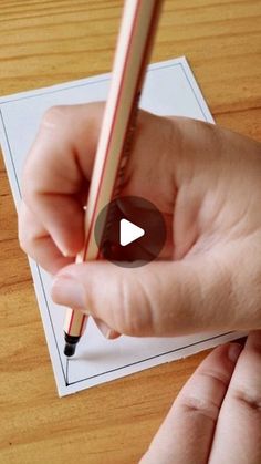 a person holding a pencil and writing on paper