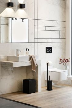 a bathroom with a toilet, sink and mirror on the wall next to each other