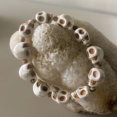 a bracelet with skulls on it sitting next to a rock