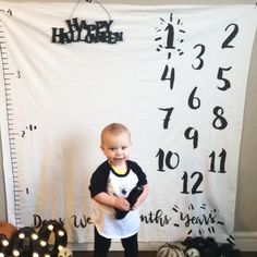 a young boy standing in front of a halloween backdrop with numbers and pumpkins on it