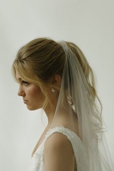 a woman in a wedding dress with a veil on her head looking off to the side