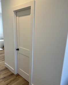 an empty room with two white doors and hard wood flooring