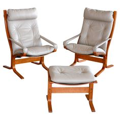 two white leather chairs sitting next to each other on top of a wooden frame and footstool