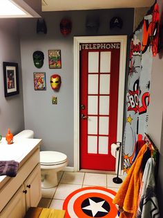 a bathroom with a red door, white toilet and black and orange decor on the walls