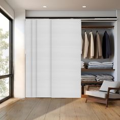 an open closet with white sliding doors and clothes on hangers in front of it