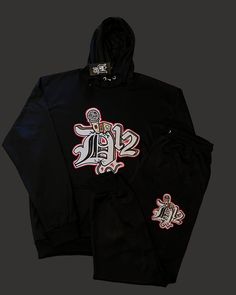 Embrace the thrill of risk-taking in the streets with the D12 Mic Check Embroidered Jogging Suit. The bold embroidered logo adds a touch of edginess to your style, while the comfortable fit allows you to conquer any adventure. Elevate your look and feel motivated to take on the challenge with this statement piece! Hip Hop Winter Tracksuit For Streetwear, Black Tracksuit With Letter Print For Streetwear, Black Letter Print Tracksuit For Streetwear, Winter Tracksuit With Graphic Print For Streetwear, Winter Graphic Print Tracksuit For Streetwear, Hooded Graphic Print Tracksuit For Streetwear, Winter Black Crew Neck Sets, Hip Hop Cotton Tracksuit For Streetwear, Winter Sportswear Tracksuit With Graphic Print