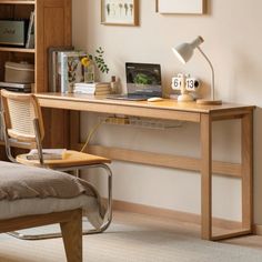 a wooden desk with a laptop on top of it next to a chair and bookshelf