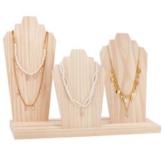 three necklaces are displayed on a wooden stand