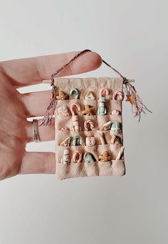 a hand is holding a small square ornament with seashells on it