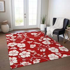 a red rug with white flowers on it in front of a chair and door way