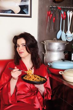 a woman in a red robe is holding a plate of food and posing for the camera