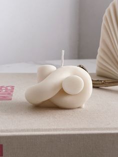 a white candle sitting on top of a box next to a hand fan and book