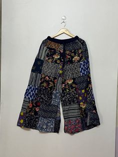 Welcome to my shop! This is a handmade Unisex Patchwork Palazzo Pant made from soft, comfortable cotton material. The length of this pant is approximately 38-40 inches and the waist measures 26 inches, stretching up to 45 inches due to the elastic material and drawstring closure. It features a regular waist style and comes in item number MG 007. The patchwork on this pant is done with different patterns, giving it a unique and bohemian look. The cute tassels add a fun touch and the elastic waist and ankle make it perfect for relaxing at home, working out, or doing yoga. This pant is made with soft rayon fabric, making it a comfortable and stylish choice. Please note that due to lighting and monitor settings, the color of the product may slightly vary. As this is a hand patchwork, there may Patchwork Long Skirt For Summer, Summer Patchwork Long Skirt, Long Skirt With Patchwork For Summer, Summer Long Skirt With Patchwork, Black Patchwork Bottoms For Summer, Cotton Patchwork Wide-leg Pants, Bohemian Wide Leg Bottoms With Patchwork, Bohemian Spring Bottoms With Floral Patchwork, Spring Bohemian Bottoms With Floral Patchwork