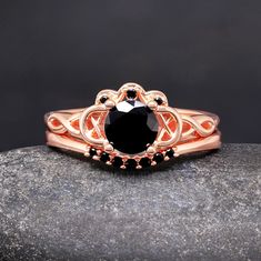 a black diamond ring sitting on top of a rock with an intricate design around it