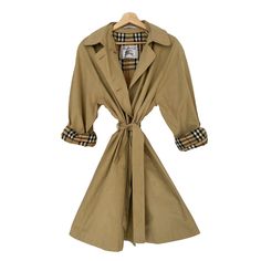 Burberry Vintage women's beige trench coat, waterproof, with an oversized design, belt and hood. It has straps on the sleeves and two side pockets where you can put your hands. It has tortoiseshell buttons. The lining is a vintage check, the traditional one from the brand (Novacheck). Made in Spain. Size S. It is in very good condition, but since the trench coat is vintage from the 90s and has a history, it could have some small imperfections, stains or signs of wear due to the passage of time o Burberry Raincoat, Trench Coat Vintage, Burberry Gifts, Trench Beige, Coat Waterproof, Beige Trench Coat, Hooded Trench Coat, Burberry Vintage, Coat Vintage