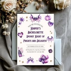 a purple and white halloween party card on top of a table next to some flowers