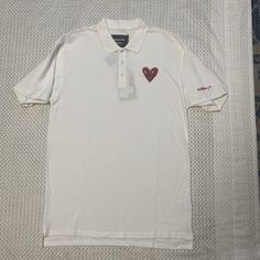 This Reason Clothing Polo Shirt Features An Embroidered Heart Design, Perfect For Any Occasion. The Shirt Is Made Of 100% Cotton And Has A Regular Fit, With Short Sleeves And A Collared Neckline. It Comes In Black And Is Available In Size L. The Shirt Is Machine Washable And Has Button Closure. It's Suitable For Various Activities Such As Tennis, Walking, School, Golf, Dance, Driving, And Fishing. The Shirt Is Part Of The Keith Haring Product Line And Is Perfect For Men Who Want To Make A Statem Casual Polo T-shirt With Embroidered Logo, Casual Collared T-shirt With Embroidered Logo, Casual Embroidered Collared Tops, Casual Embroidered Polo Collar Top, Casual Embroidered Cotton Polo Shirt, Casual Cotton Embroidered Polo Shirt, Embroidered Cotton Polo Collar Tops, Casual Cotton Shirt With Heart Print, Embroidered Cotton Polo Shirt