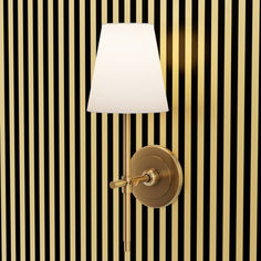 a lamp on a wall next to a striped wallpapered room with black and gold stripes