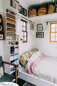 a bed sitting under a window next to a shelf filled with pictures and other items