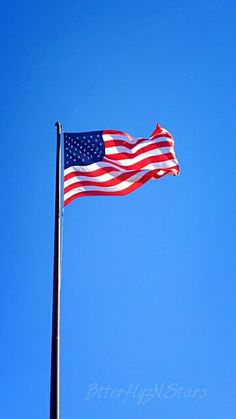 an american flag flying in the wind on a clear day with blue sky behind it