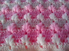 a pink and white crocheted blanket with leaves on it