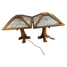 two wooden table lamps with glass shades on each side and an electric cord in the middle